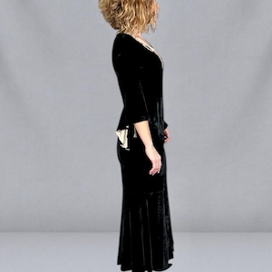Puede incluir: Un vestido de terciopelo negro con escote en V y mangas tres cuartos. El vestido tiene un corpi&ntilde;o ajustado y una falda acampanada, y se combina con tacones altos negros. El vestido tiene un ribete color crema.