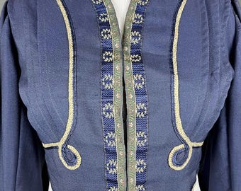 Puede incluir: Chaqueta azul marino con adornos detallados. La chaqueta presenta un diseño de cuello en V con adornos decorativos en los bordes y un patrón detallado en la parte delantera. Las mangas son largas y la chaqueta tiene un corte corto.
