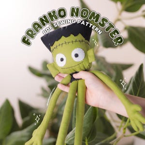 May include: A green plush doll with a black hair section, stitched forehead detail, and large white eyes with black pupils. The text FRANKO NOMSTER PDF SEWING PATTERN is arched above the doll. The doll has long, thin arms and legs.