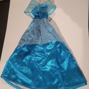 Puede incluir: Un vestido de bola de tul y satén azul y blanco con una superposición de tul azul transparente y detalles de purpurina plateada. El vestido tiene un corpiño ajustado y una falda completa.