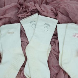 Three pairs of white grip socks for pilates with different bridal icons on them