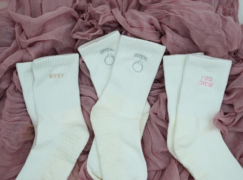 Three pairs of white grip socks for pilates with different bridal icons on them