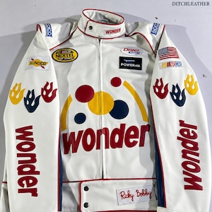 May include: A white racing jacket featuring red, yellow, and blue circular accents and the word wonder in red lettering. The jacket includes various sponsor patches, including NASCAR Nextel Cup Series, Sundco, Dennit Racing, Powerade, and an American flag.