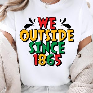 May include: White t-shirt with the text "WE OUTSIDE SINCE 1865" in red, yellow, green, and black. The shirt has a crew neck and short sleeves. The text is in a bold, colorful font.