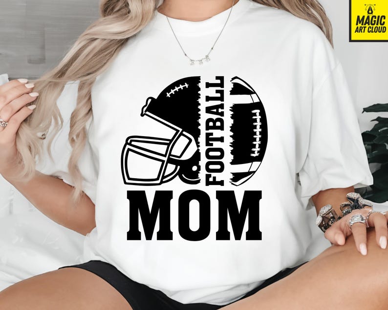 Puede incluir: Camiseta blanca con un dise&ntilde;o de casco y bal&oacute;n de f&uacute;tbol en blanco y negro. Las palabras "FOOTBALL MOM" est&aacute;n impresas en letras negras en negrita. Un gran regalo para las madres futbolistas.
