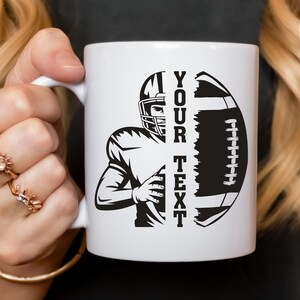 Puede incluir: Taza de cer&aacute;mica blanca con un dise&ntilde;o de f&uacute;tbol americano en blanco y negro. El dise&ntilde;o incluye un jugador y un bal&oacute;n de f&uacute;tbol, con las palabras "YOUR TEXT" impresas verticalmente. La taza tiene un asa blanca.