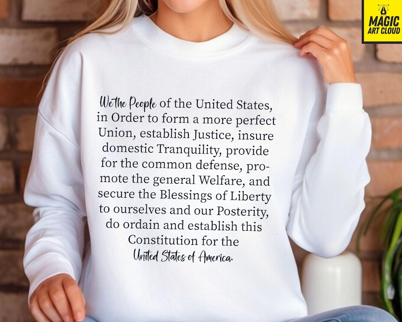 May include: White sweatshirt with the text "We the People of the United States, in Order to form a more perfect Union, establish Justice, insure domestic Tranquility, provide for the common defence, promote the general Welfare, and secure the Blessings of Liberty to ourselves and our Posterity, do ordain and establish this Constitution for the United States of America."