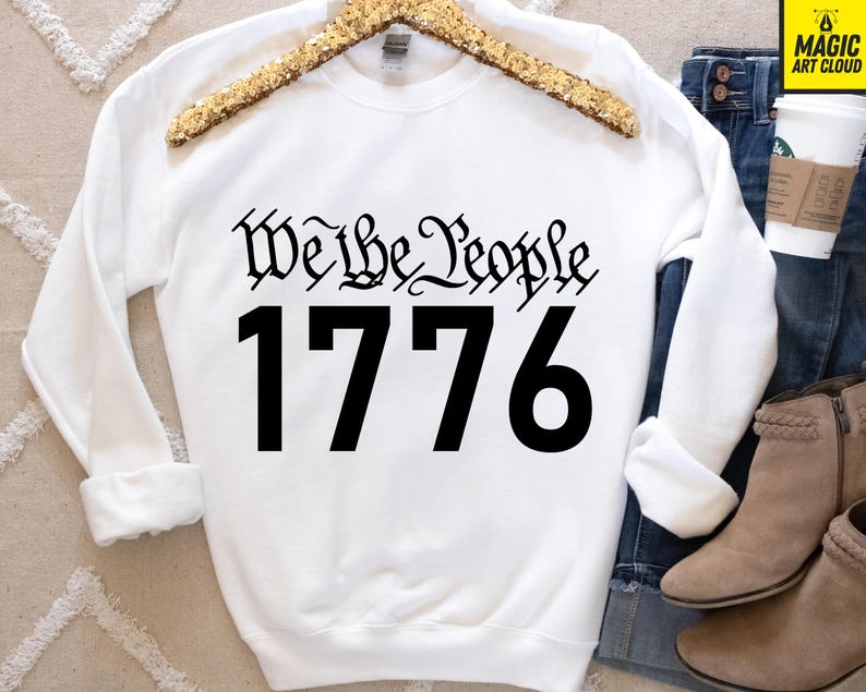 May include: White sweatshirt with black text that reads "We the People 1776".