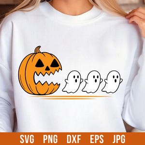 Puede incluir: Sudadera blanca con un diseño de Halloween. Una calabaza naranja con una cara tallada está a la izquierda, con tres fantasmas blancos a la derecha. La parte inferior de la sudadera tiene las palabras "SVG PNG DXF EPS JPG".