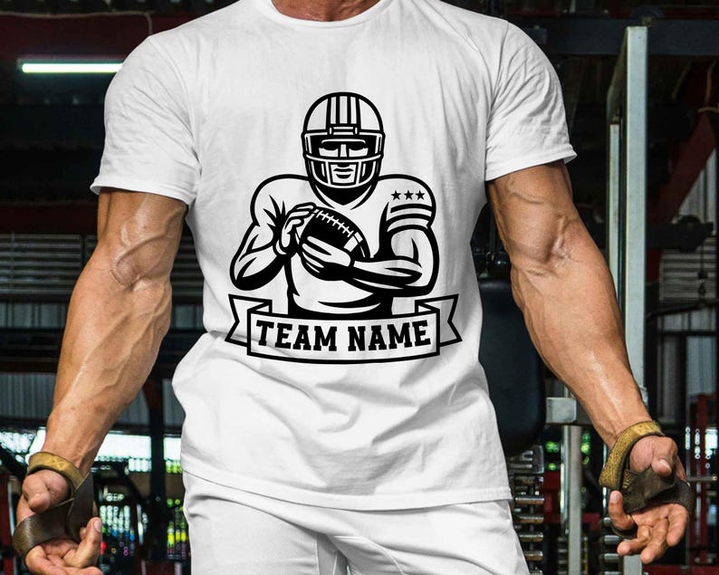 Puede incluir: Camiseta blanca con una ilustraci&oacute;n en blanco y negro de un jugador de f&uacute;tbol americano con casco, sosteniendo un bal&oacute;n. El dise&ntilde;o incluye una pancarta con el texto "TEAM NAME".