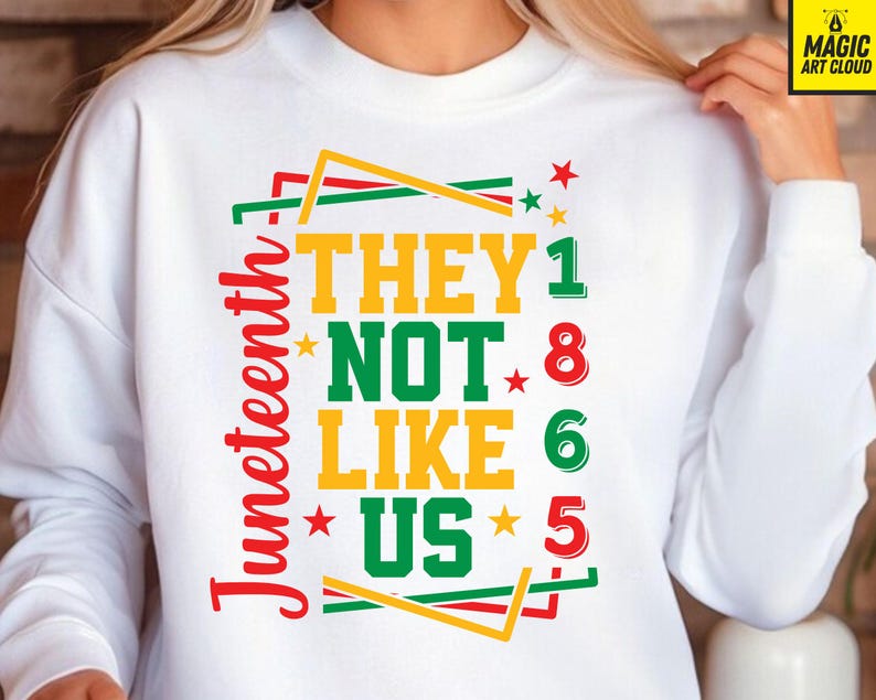 May include: White sweatshirt with a colorful graphic design. The design features the text "THEY NOT LIKE US" in yellow and green, with the word "Juneteenth" in red. The design also includes stars and the numbers 1, 8, 6, and 5.