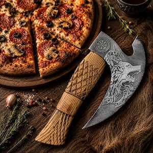 Könnte beinhalten: Ein Pizzaschneider aus Metall mit einer geschwungenen Klinge, die einen eingravierten Wolfskopf und ein kreisförmiges Runensymbol zeigt. Der Griff besteht aus hellem Holz mit einem geschnitzten Rautenmuster und vertikalen Rillen.