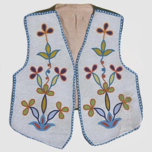 Puede incluir: Un chaleco blanco con cuentas y un diseño floral. El chaleco presenta un ribete azul y un interior beige. El patrón floral incluye cuentas rojas, amarillas, azules y verdes. Prenda tradicional.