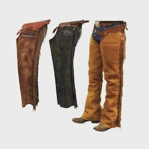 Könnte beinhalten: Drei Paar Lederchaps in verschiedenen Braun- und Schwarztönen. Die Chaps haben Fransen an den Seiten und dekorative Nähte. Ein Paar wird mit blauen Jeans und Cowboy-Stiefeln getragen.