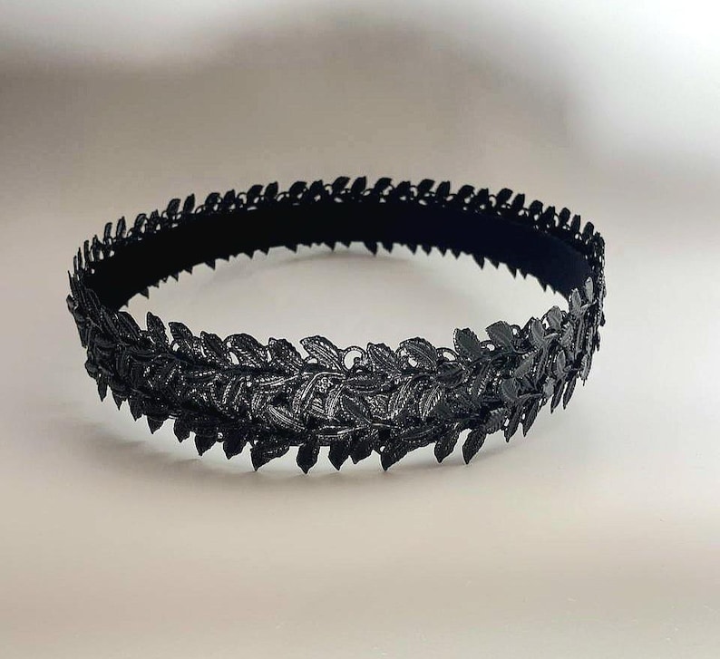 Puede incluir: Una corona de hojas negra, con intrincados detalles de hojas. La corona est&aacute; hecha de un material oscuro y est&aacute; dise&ntilde;ada para ser usada alrededor de la cabeza. Las hojas est&aacute;n dispuestas en un patr&oacute;n circular, creando un adorno para la cabeza decorativo.