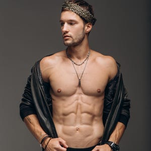 Puede incluir: Una corona de laurel met&aacute;lica sobre la cabeza, combinada con una chaqueta de cuero negra, collares de cadena plateada superpuestos, un reloj de pulsera negro y pulseras de cuentas apiladas, con pantalones vaqueros negros.