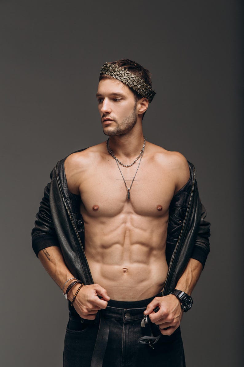 Puede incluir: Una corona de laurel met&aacute;lica sobre la cabeza, combinada con una chaqueta de cuero negra, collares de cadena plateada superpuestos, un reloj de pulsera negro y pulseras de cuentas apiladas, con pantalones vaqueros negros.