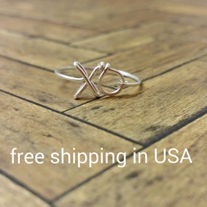 May include: A silver ring with a wire design that forms the letters "XO".