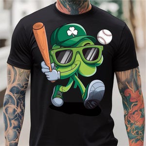 May include: A black t-shirt featuring a green cartoon clover wearing sunglasses and a baseball cap, holding a baseball bat and a baseball.