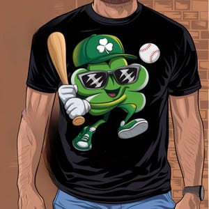May include: A black t-shirt featuring a green cartoon clover wearing sunglasses and holding a baseball bat. The clover is wearing a green and white baseball cap with a shamrock on it. A baseball is in the background.