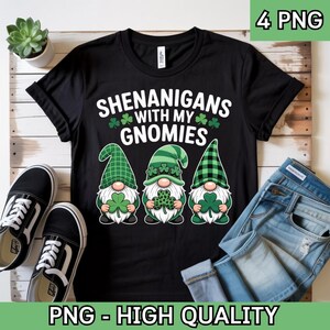 May include: Black t-shirt with the text "SHENANIGANS WITH MY GNOMIES" and three gnome illustrations holding shamrocks. The gnomes wear green hats and have white beards. The image also includes a pair of black and white sneakers and blue jeans.