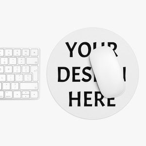 May include: White round mouse pad with the text "YOUR DESIGN HERE" in black lettering. A white computer mouse is on top of the mouse pad.