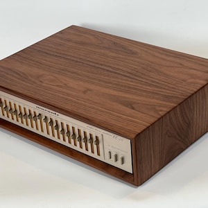 May include: A vintage Marantz EQ-20 graphic stereo equalizer with a wood grain finish. The faceplate is silver with multiple sliders and control knobs. The Marantz logo is visible.