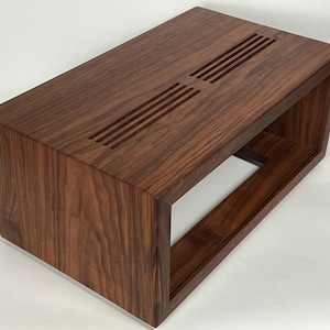 May include: A rectangular, open-shelf wooden cabinet with a rich, dark brown finish. The top surface features three parallel rows of evenly spaced, narrow slots. The cabinet's design is modern and minimalist, with clean lines and a focus on the natural wood grain.