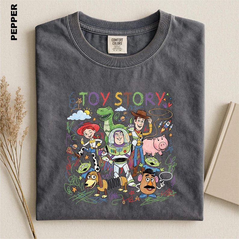 A gray t-shirt with a colorful graphic design featuring characters from the Toy Story movie, including Woody, Buzz Lightyear, and Piggy.
