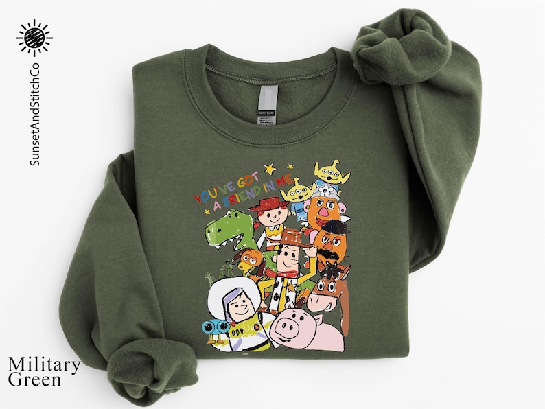 A green sweatshirt with a colorful graphic of various cartoon characters from the Toy Story franchise, including Woody, Buzz Lightyear, and other beloved characters.