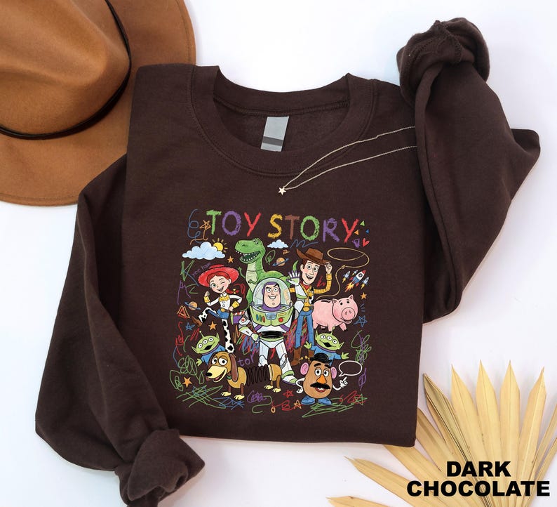 A brown sweatshirt with a colorful graphic of characters from the Toy Story movie, including Woody, Buzz Lightyear, and other beloved characters, along with the text "TOY STORY".