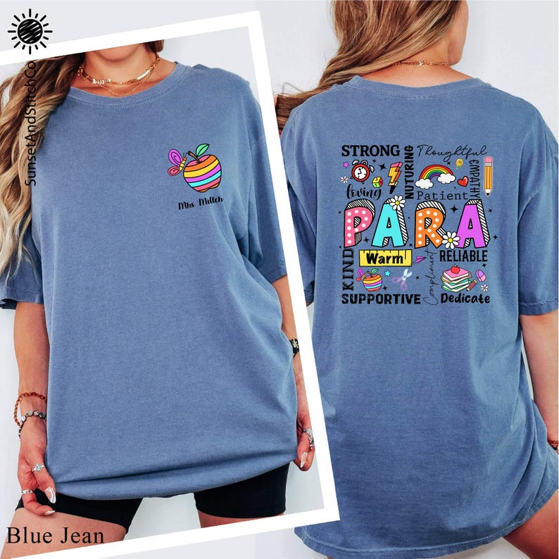 A woman wearing a blue t-shirt with a colorful design and text printed on the back.