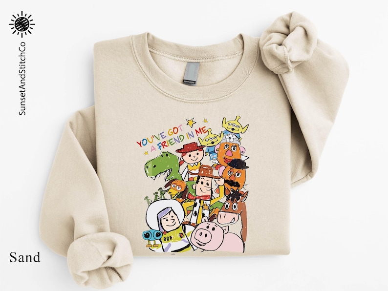 A beige sweatshirt with a colorful graphic design featuring various cartoon characters from the Toy Story franchise.