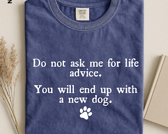 May include: A navy blue crew neck t-shirt featuring the white printed text "Do not ask me for life advice. You will end up with a new dog." and a small white paw print icon below the text. The shirt has a Comfort Colors brand label at the neck.