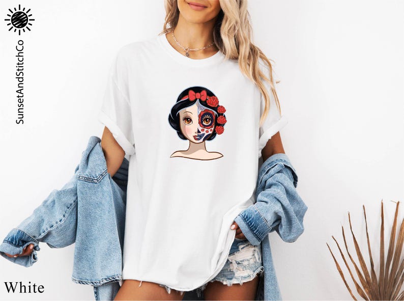 A woman wearing a white t-shirt with a colorful graphic of a woman's face and floral elements.