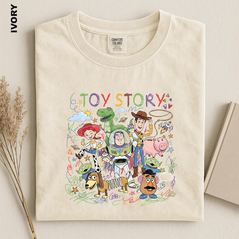 A beige t-shirt with a colorful illustration of characters from the Toy Story movie, including Woody, Buzz Lightyear, and other beloved characters.