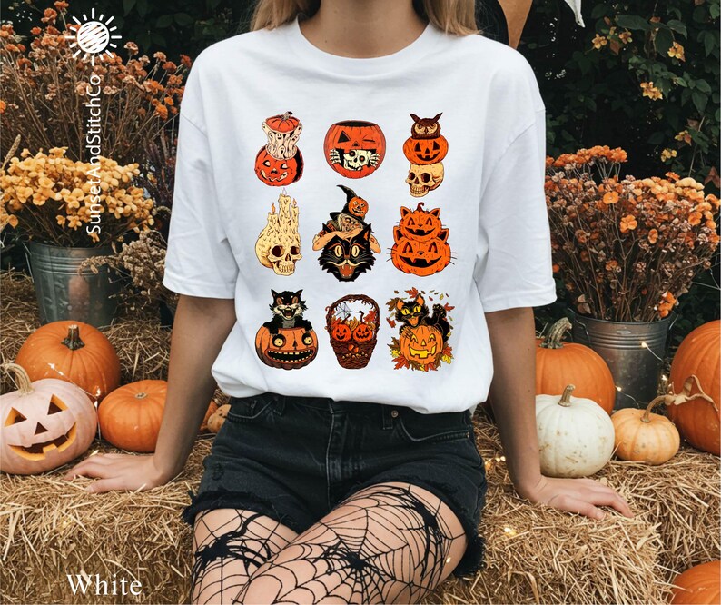 A woman wearing a white t-shirt with a graphic of Halloween-themed cats and pumpkins, surrounded by pumpkins, flowers, and a spooky atmosphere.