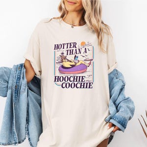 A woman wearing a white t-shirt with a graphic design and text printed on it.