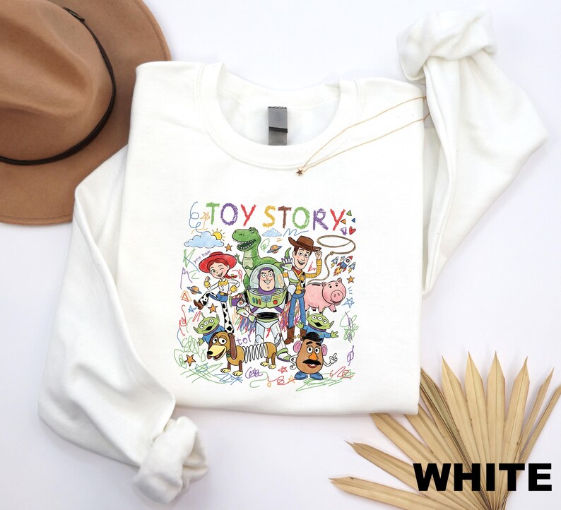 A white long-sleeved shirt with a colorful illustration of characters from the Toy Story movie, including Woody, Buzz Lightyear, and other beloved characters.