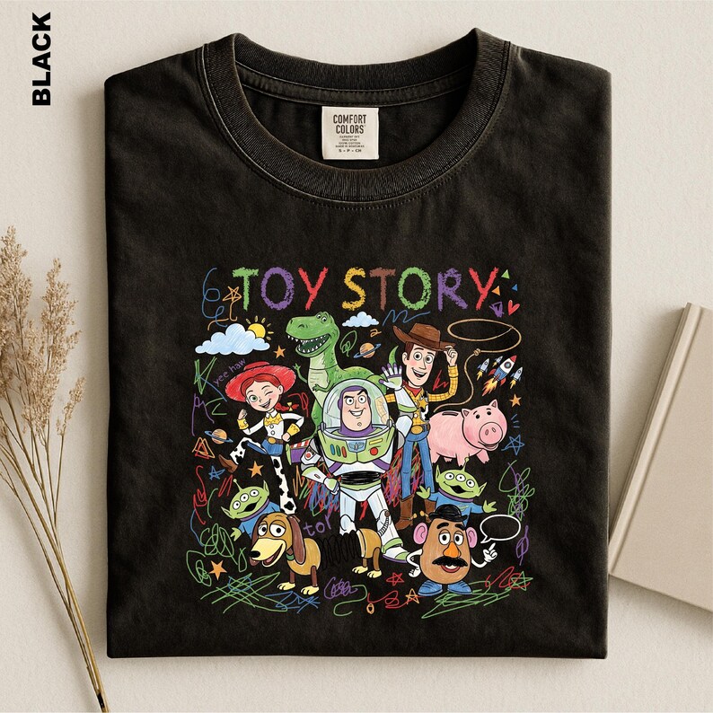A black t-shirt with a colorful graphic design featuring characters from the Toy Story movie, including Woody, Buzz Lightyear, and other beloved characters.