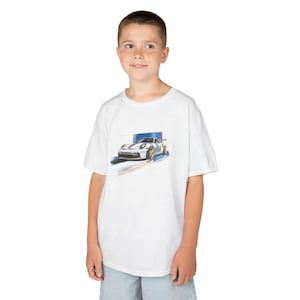Op de afbeelding: Wit T-shirt met een aquarel illustratie van een witte sportwagen met blauwe en gouden accenten. De auto wordt in beweging getoond tegen een blauwe achtergrond. Het T-shirt wordt door een persoon gedragen.