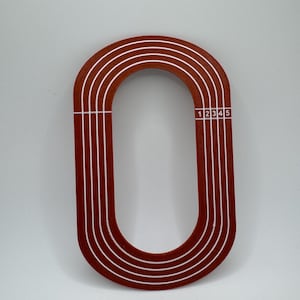 May include: A red wooden cutout of a running track with five lanes. The lanes are numbered 1 through 5.