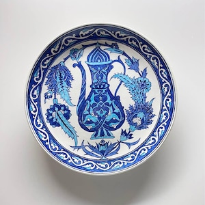 May include: A white ceramic mug with a black handle and the text "But First, Coffee" in a black, handwritten-style font. The mug is on a white surface.