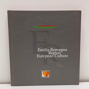 May include: A dark gray book titled "Emilia-Romagna Region European Culture." The cover features a large stylized "F" and the text in white. The book has a small emblem with a portrait and the words "Cultura d'Europa."