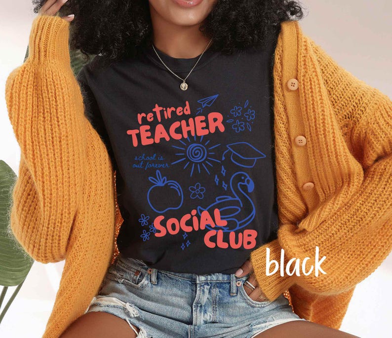 May include: Black t-shirt with the words "Retired Teacher Social Club" in red and blue, with illustrations of a sun, apple, graduation cap, and flamingo. The shirt is worn with a gold cardigan and denim shorts.