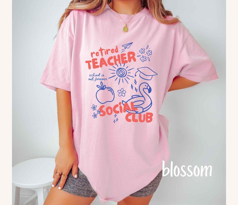 May include: A light pink t-shirt with a graphic design that reads "retired TEACHER SOCIAL CLUB". The design includes a sun, apple, flamingo, and other illustrations in blue and red. The text "school is out forever" is also included.