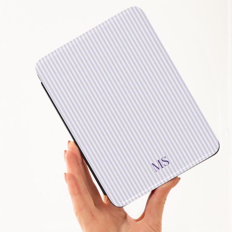 May include: A rectangular case with a white and light purple striped pattern. The case has the initials "MS" in the bottom right corner. The case is held in a person's hand.