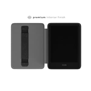 May include: A gray e-reader case with a black hand strap is open, revealing a black e-reader with the brand name "Kindle" at the bottom. The text "premium interior finish" is above the case.
