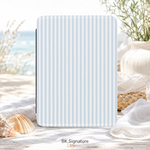Peut inclure: Une housse de liseuse électronique rectangulaire présentant un motif à rayures verticales bleu clair et blanc. La housse a une surface lisse et plate et est positionnée à la verticale. Le texte BK Signature est imprimé en bas au centre.