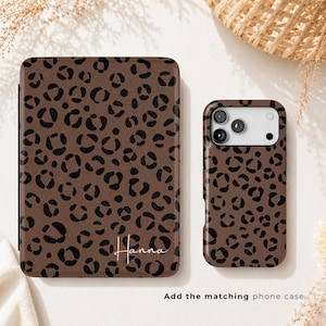 May include: A rectangular tablet case and a matching smartphone case, both featuring a brown background with a black leopard print pattern. The tablet case displays the name Hanna in white script text in the bottom right corner.